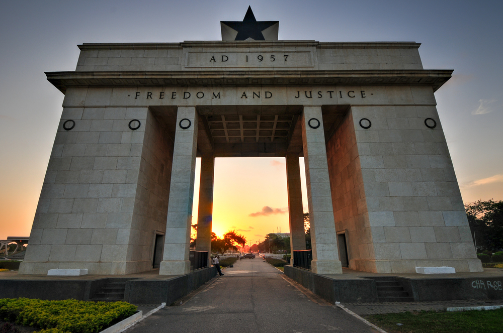 Independence Square's Black Star Gate at sunset, inscribed 'AD 1957 · Freedom and Justice'